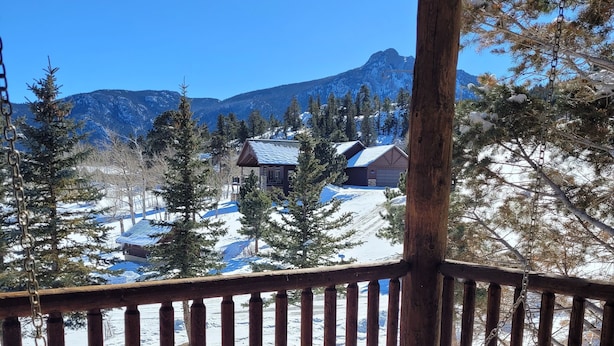 A wooden bench on a porch overlooking a snowy landscape with mountains in the background. - Kruger Rock Condo #6189 (Estes Park)