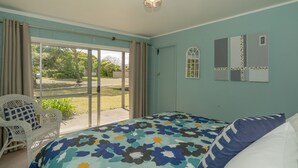 Um quarto com uma cama, uma cadeira, uma janela e uma porta.