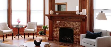 A spacious living room with a fireplace, comfortable seating, and a modern chandelier.