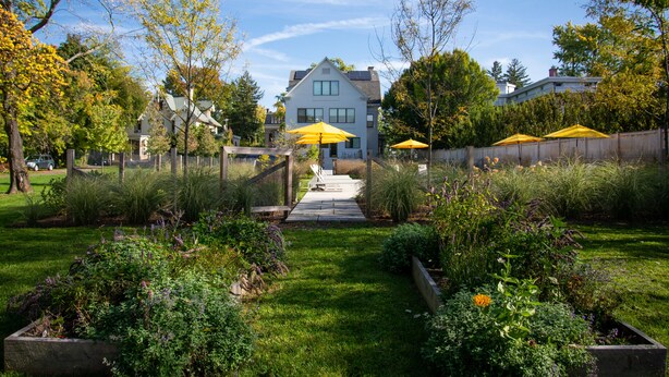 A residential garden with a pathway leading to a house. - The Amelia (Hudson)