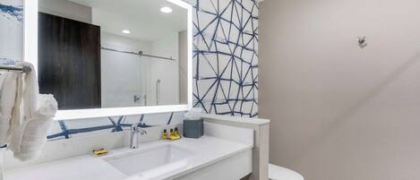 A modern bathroom with a white sink, mirror, and toilet.