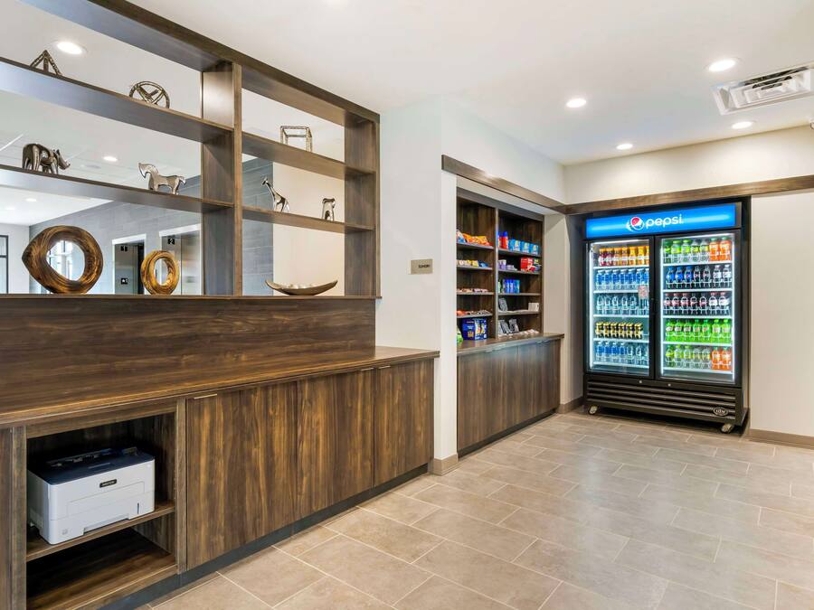 A reception area with a wooden reception desk, a Pepsi refrigerator, and a printer on a shelf.