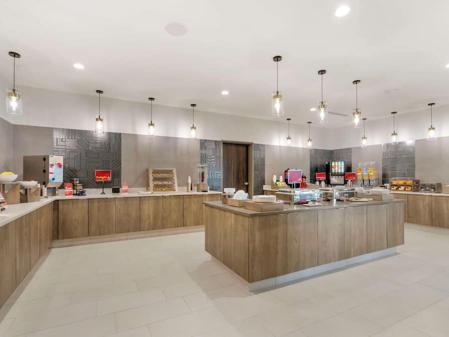 Un moderno vestíbulo de hotel con un mostrador de recepción central, varias luminarias y un papel tapiz decorativo.