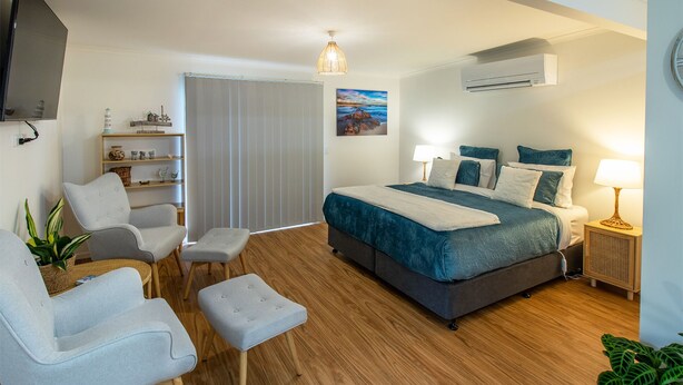 Un dormitorio moderno con una cama grande, lámparas de noche, televisión y vistas al exterior.