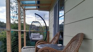 Una terraza de madera con mobiliario de mimbre y una silla colgante.
