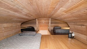 A compact attic bedroom with two beds, wooden walls, and a sloped ceiling. - Beautiful quiet space located in the heart of Merritt suburbs. (Merritt)
