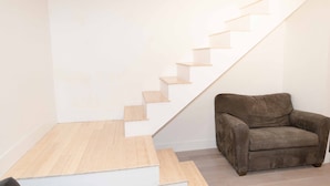 A modern staircase with wooden steps and a brown leather chair in a minimalist room. - Beautiful quiet space located in the heart of Merritt suburbs. (Merritt)
