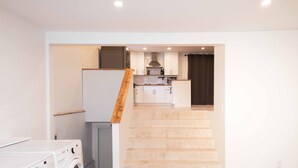 A laundry area with a washing machine and dryer, a staircase leading to a kitchen with white cabinets and a stainless steel range hood. - Beautiful quiet space located in the heart of Merritt suburbs. (Merritt)