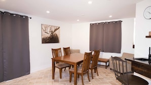 A dining area with a wooden table and chairs, a painting on the wall, and a kitchen area with a sink. - Beautiful quiet space located in the heart of Merritt suburbs. (Merritt)