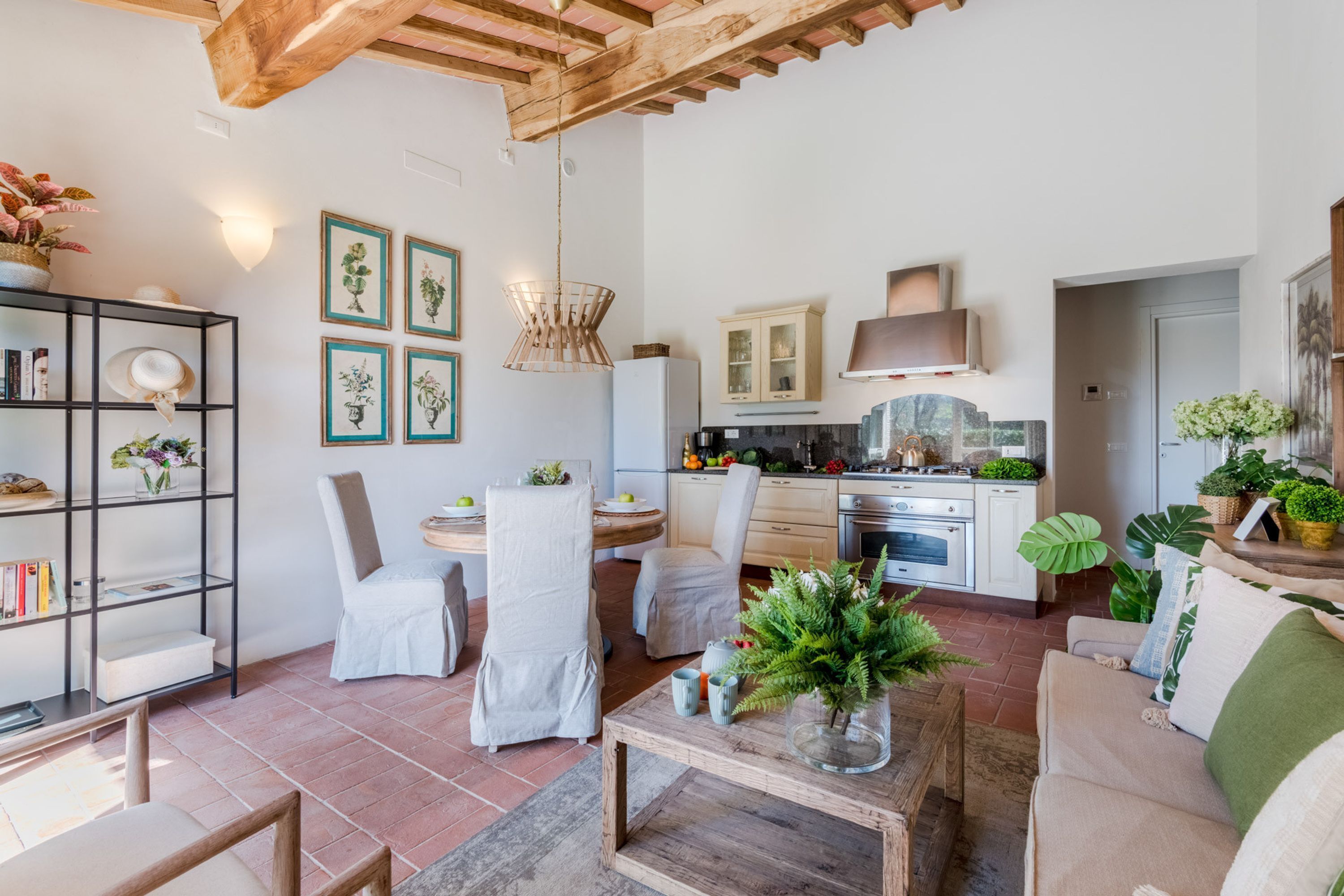 A modern kitchen with white cabinets, a wooden ceiling, and a dining area with chairs and a table.