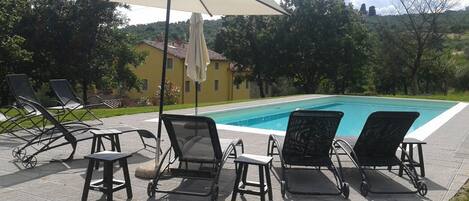A poolside area with lounge chairs, a table, and an umbrella.