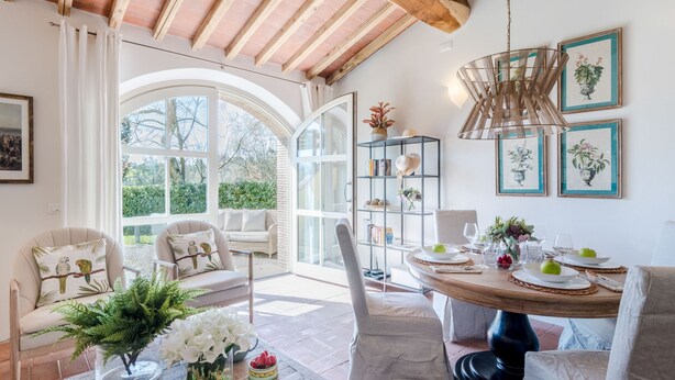 A bright, open-plan living area with a dining table set for four, surrounded by comfortable seating. - Casa Pinocchio at Borghetto Farmhouse (Capannori)