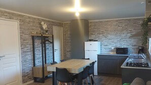 Un espacio habitable compacto con comedor, kitchenette y un sofá con cojines de colores.