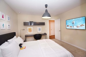A bedroom with a bed, a desk, a chair, a ceiling light, and a wall-mounted TV. - Family Getaway: Game Room, Themed Rooms & Private Yard Near Disney, BBQ!! (Kissimmee)