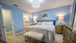 Une chambre à coucher avec un lit, un banc, une commode et des lampes.
