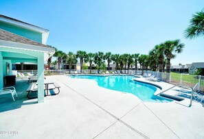 A swimming pool with lounge chairs and a covered patio area.