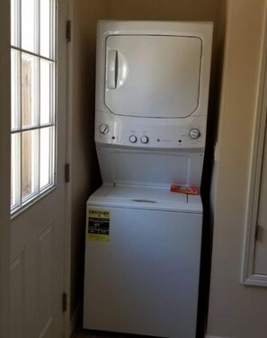 Compact laundry room with a front-loading washer and dryer, featuring a window for natural light.