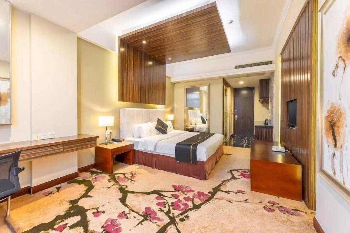 A hotel room with a bed, desk, and a large mirror.