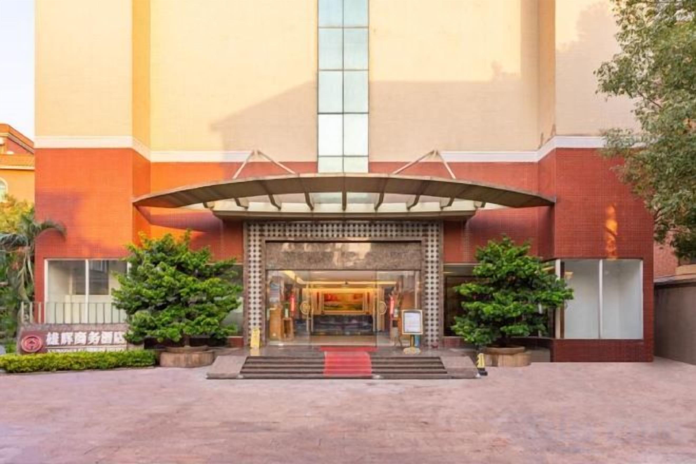 A hotel entrance with a covered walkway, a red carpet, and a vertical glass window.