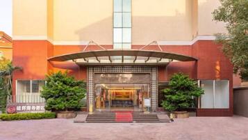A hotel entrance with a covered walkway, a red carpet, and a vertical glass window.