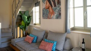 En moderne stue med sofa, rundt bord og trappe.