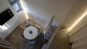 Et moderne interiør med en trappe, et rundt spisebord med stole, og et lille vindue.