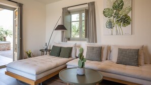 Ett modernt vardagsrum med en soffa, en säng, ett runt soffbord och en krukväxt.