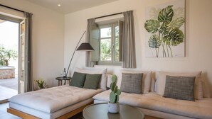 Ett modernt vardagsrum med en soffa, en säng, ett runt soffbord och ett fönster med gardiner.