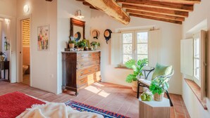 A spacious room with a wooden ceiling, a large wooden dresser, a red rug, and a window with a view of the outdoors. - Casa Noscali at Borghetto Farmhouse (Capannori)