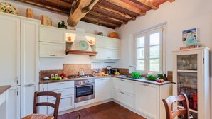 A kitchen with white cabinets, a stove, and a window. - Casa Noscali at Borghetto Farmhouse (Capannori)