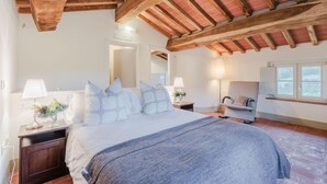 Un dormitorio con una cama grande, vigas de madera, un escritorio y una silla.