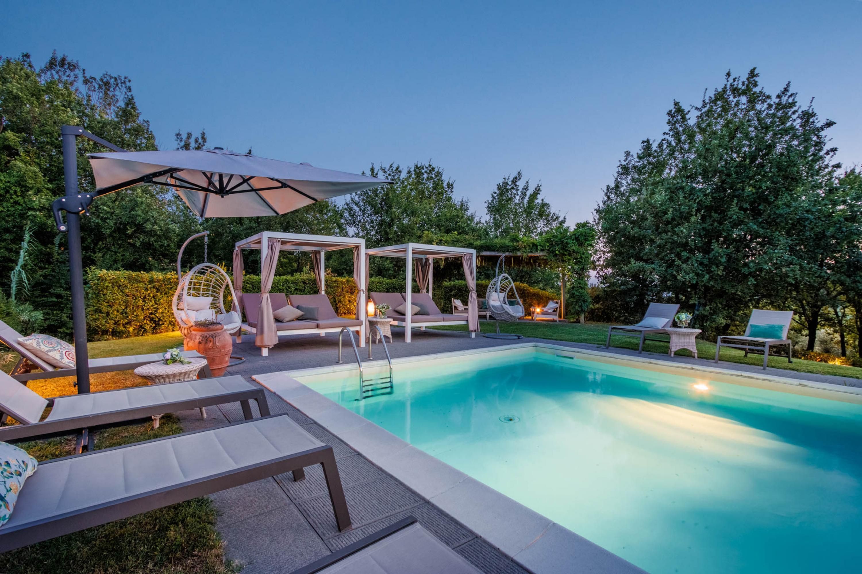 Un espace aménagé au bord de la piscine, avec des chaises longues, une pergola et une chaise suspendue.