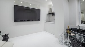A modern kitchen with white cabinetry, a large black refrigerator, and a glass coffee table with a decorative item.