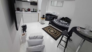 A compact living space with a kitchenette, a black bathtub, and a dining area with a small table and chairs.