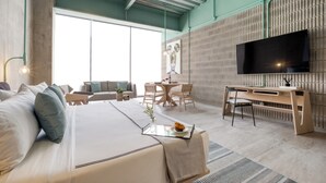 Una habitación de hotel moderna con una cama grande, un escritorio, una silla, una mesa de comedor y un televisor.