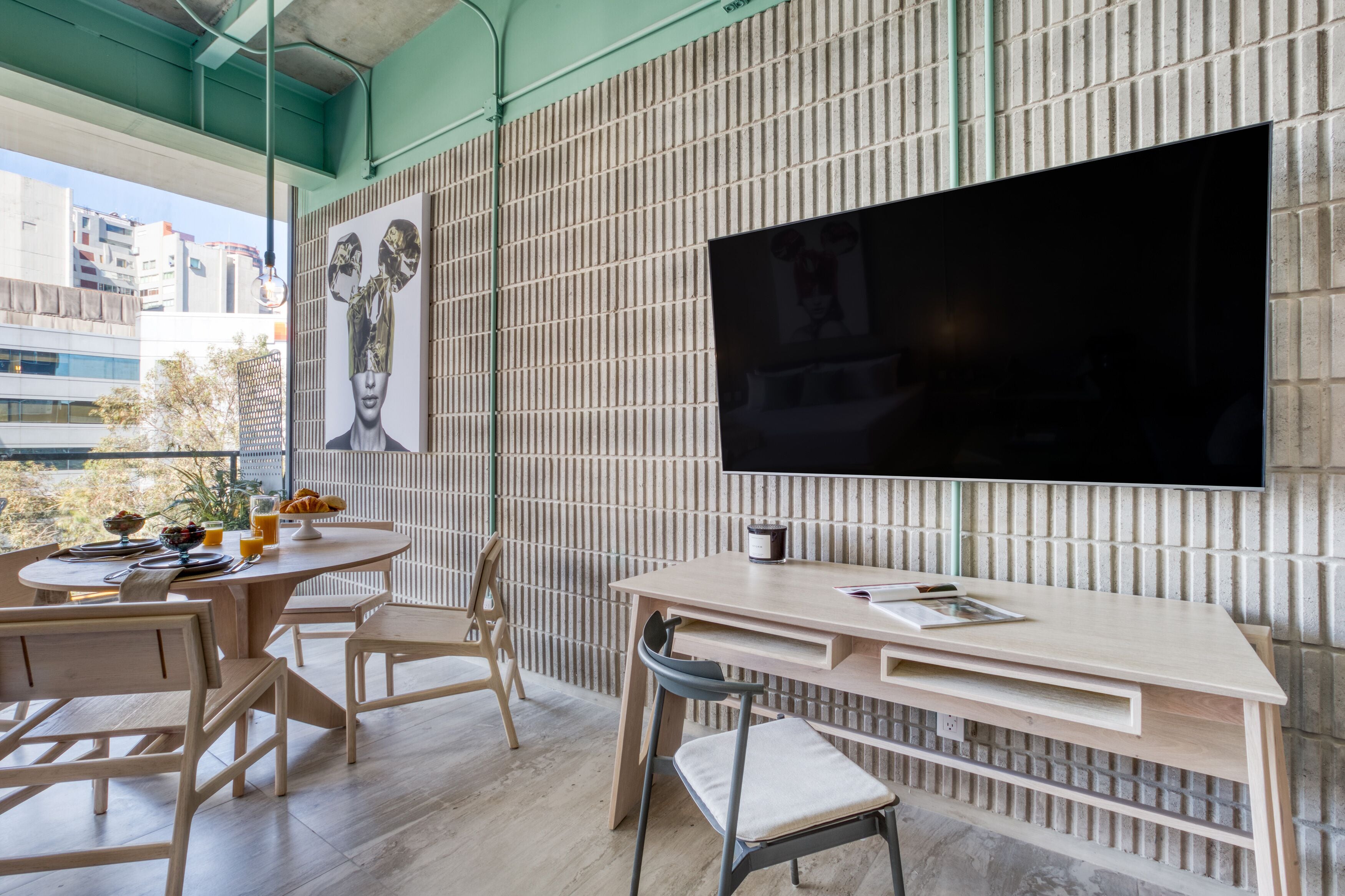 A modern dining area with a large TV, wooden furniture, and a city view.