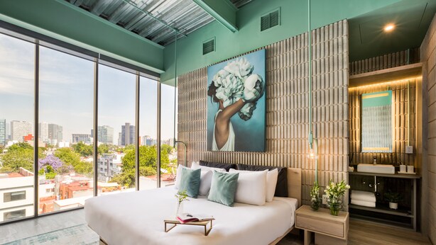 Un dormitorio moderno con una cama grande, vistas a la ciudad y un adorno en la pared.