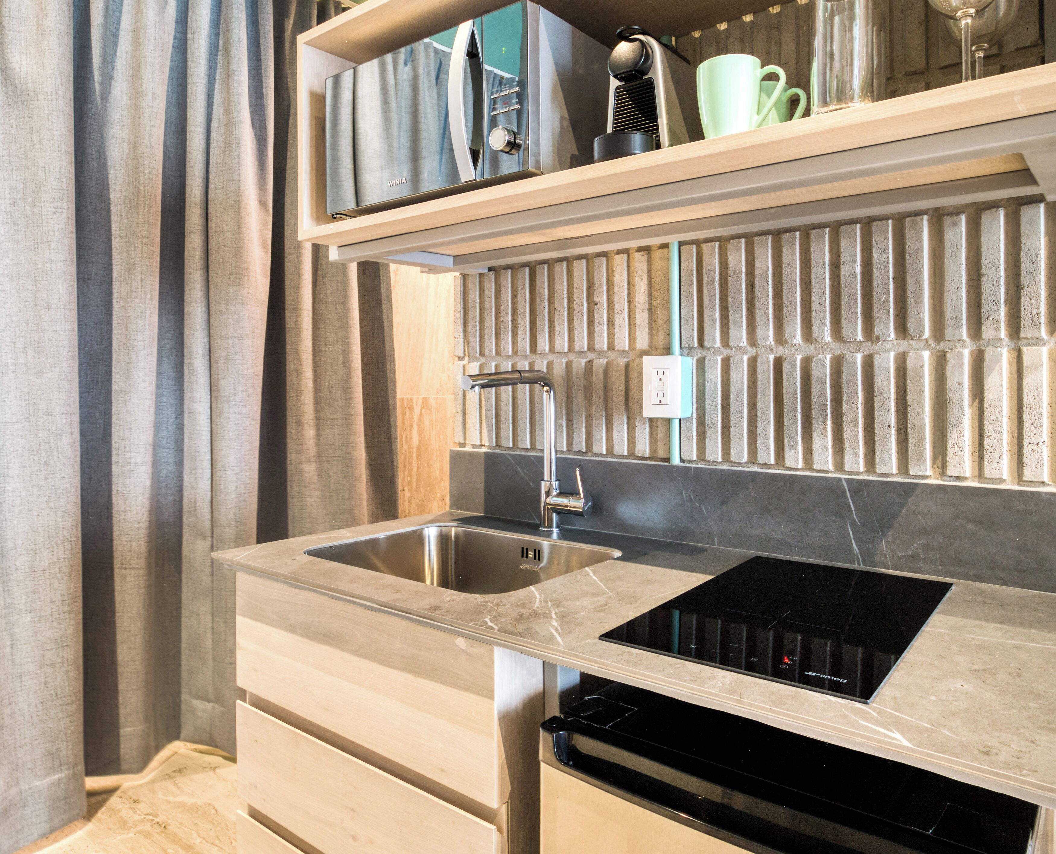 A modern kitchen with a built-in sink, a black induction cooktop, and a wooden countertop.