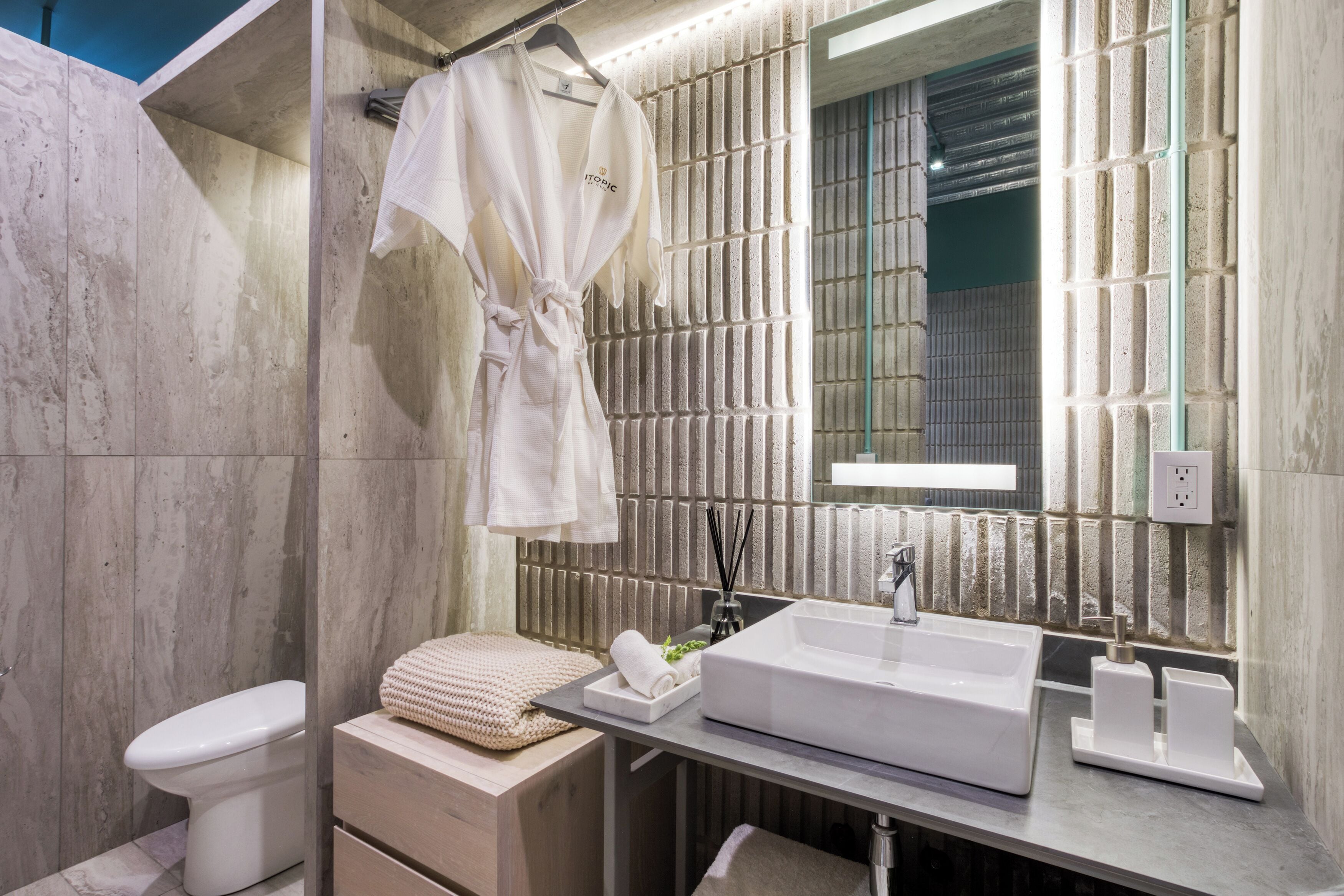 Un baño moderno con un espejo grande, un lavabo blanco y un perchero para toallas.