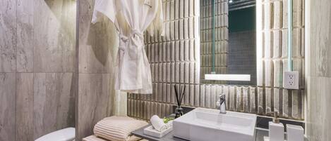 Un baño moderno con un espejo grande, un lavabo blanco y un perchero para toallas.