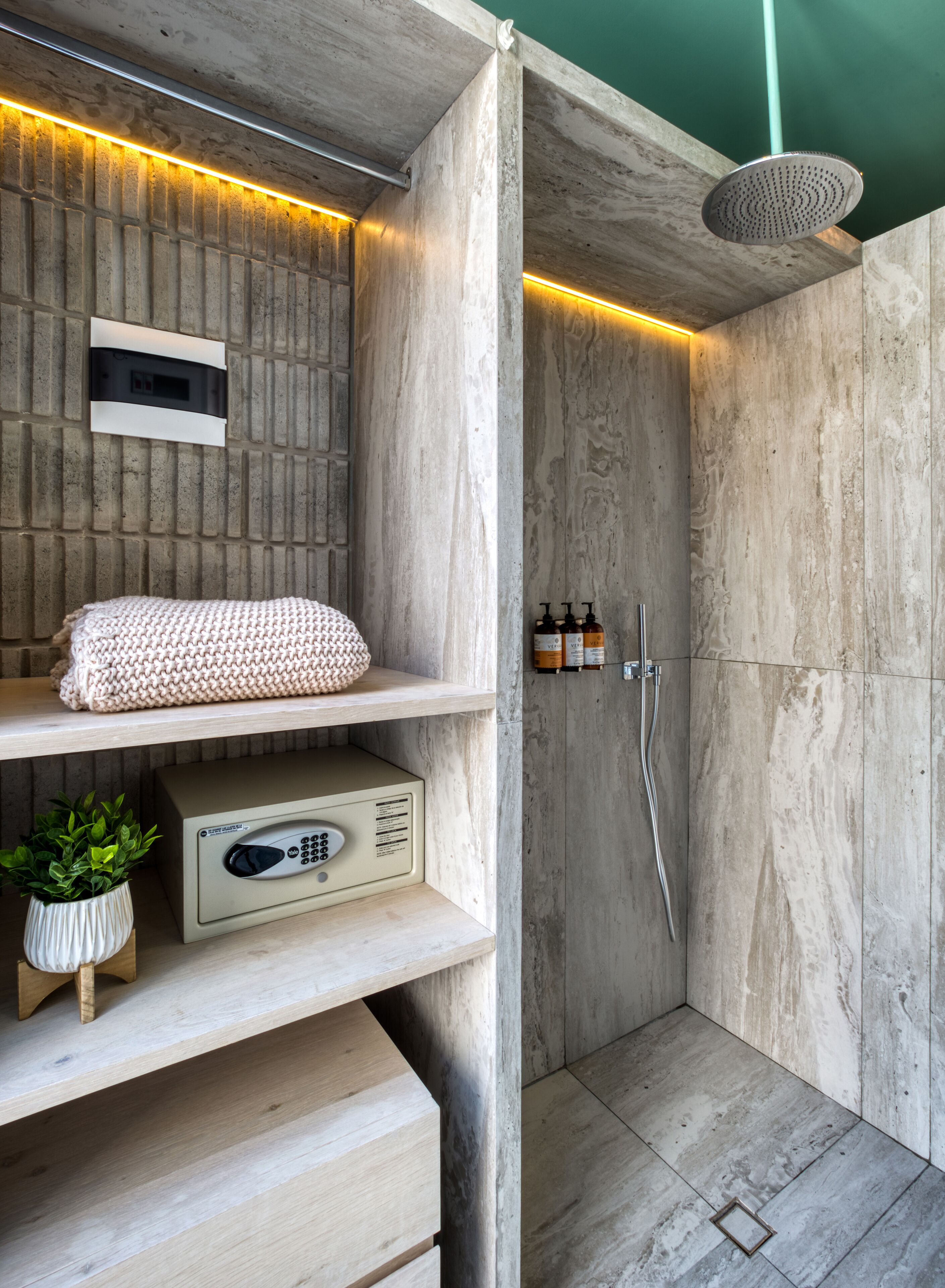 Une salle de bain moderne avec un meuble-lavabo en bois, une serviette, une plante et une douche équipée d’un pommeau de douche à main.