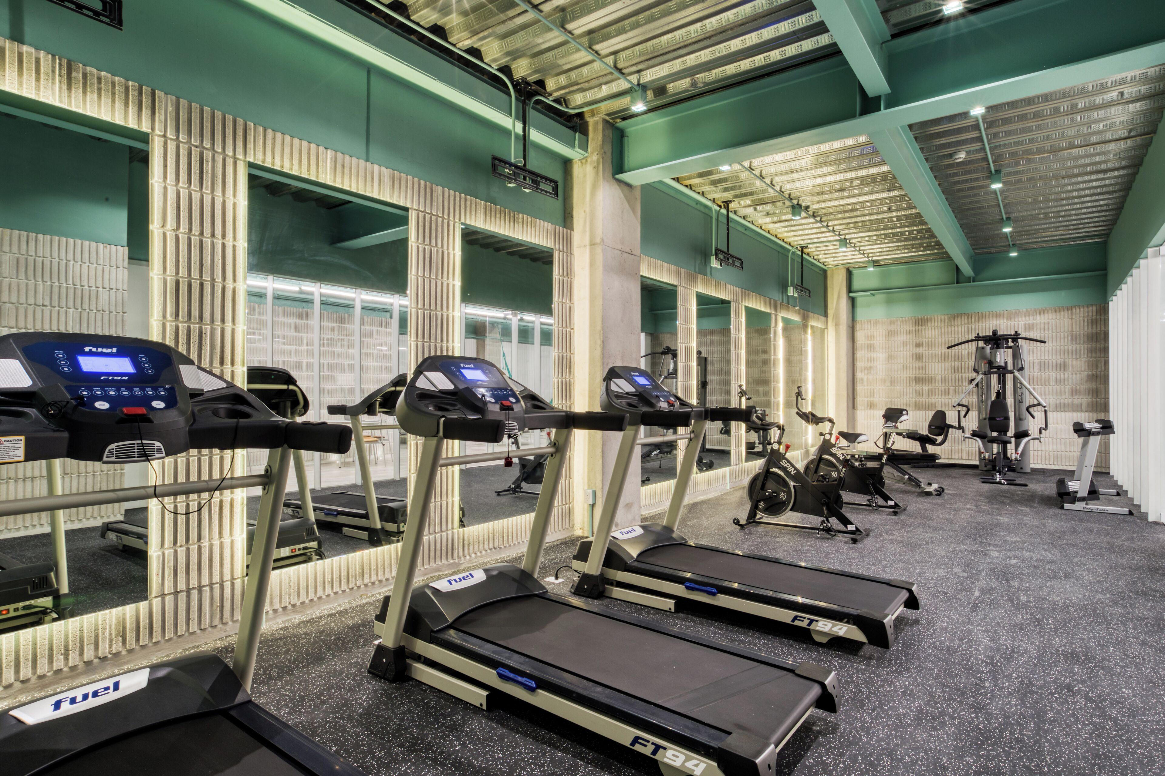 Un gimnasio con cintas de correr, bicicletas estáticas y máquinas de pesas.
