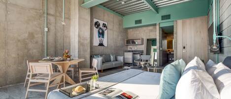 Una habitación de hotel moderna con una cama grande, un comedor y una kitchenette.