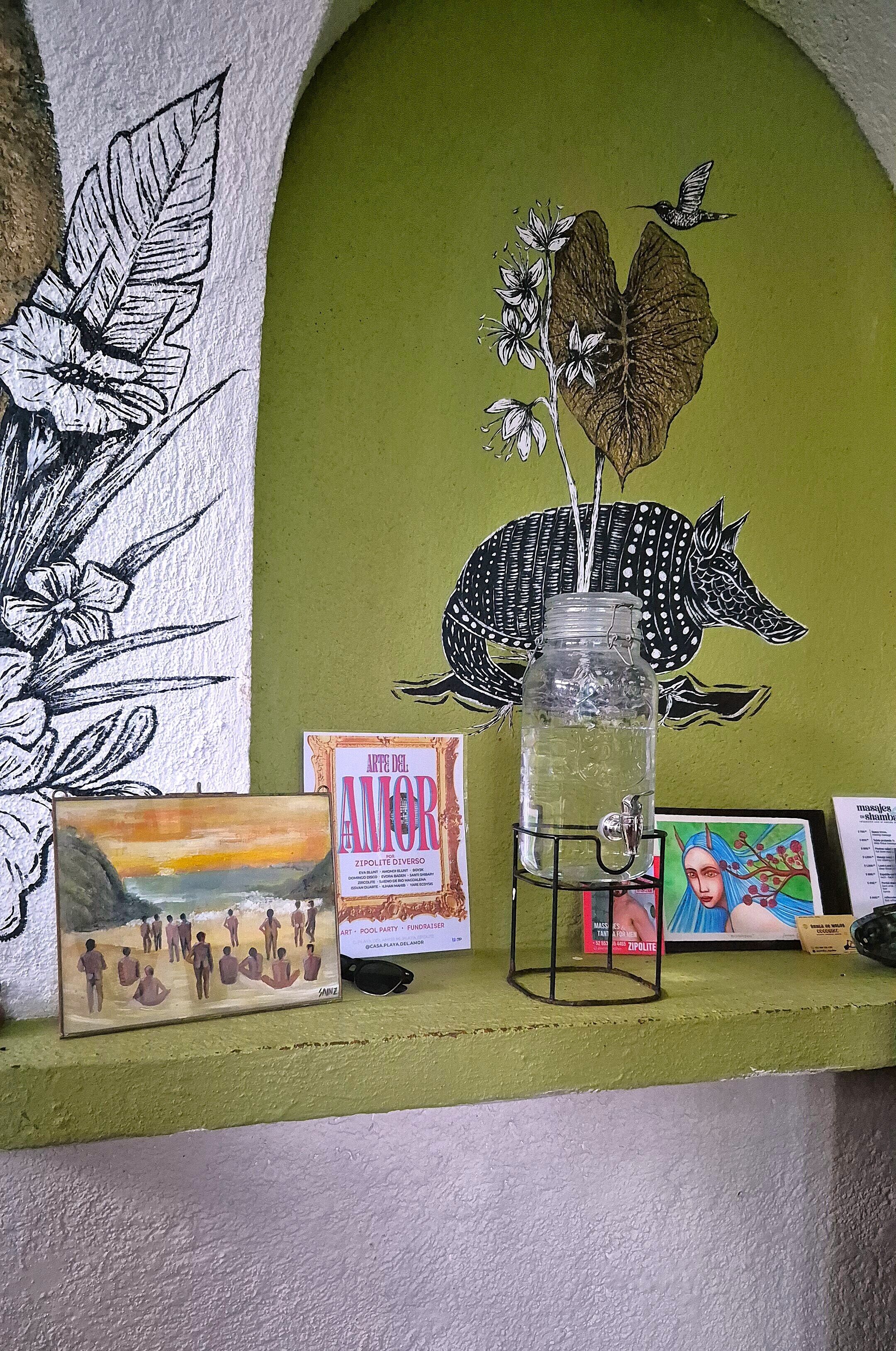 A shelf with a glass jar, a framed painting, and a book titled 'ART DEL AMOR'.