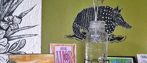 A shelf with a glass jar, a framed painting, and a book titled 'ART DEL AMOR'.