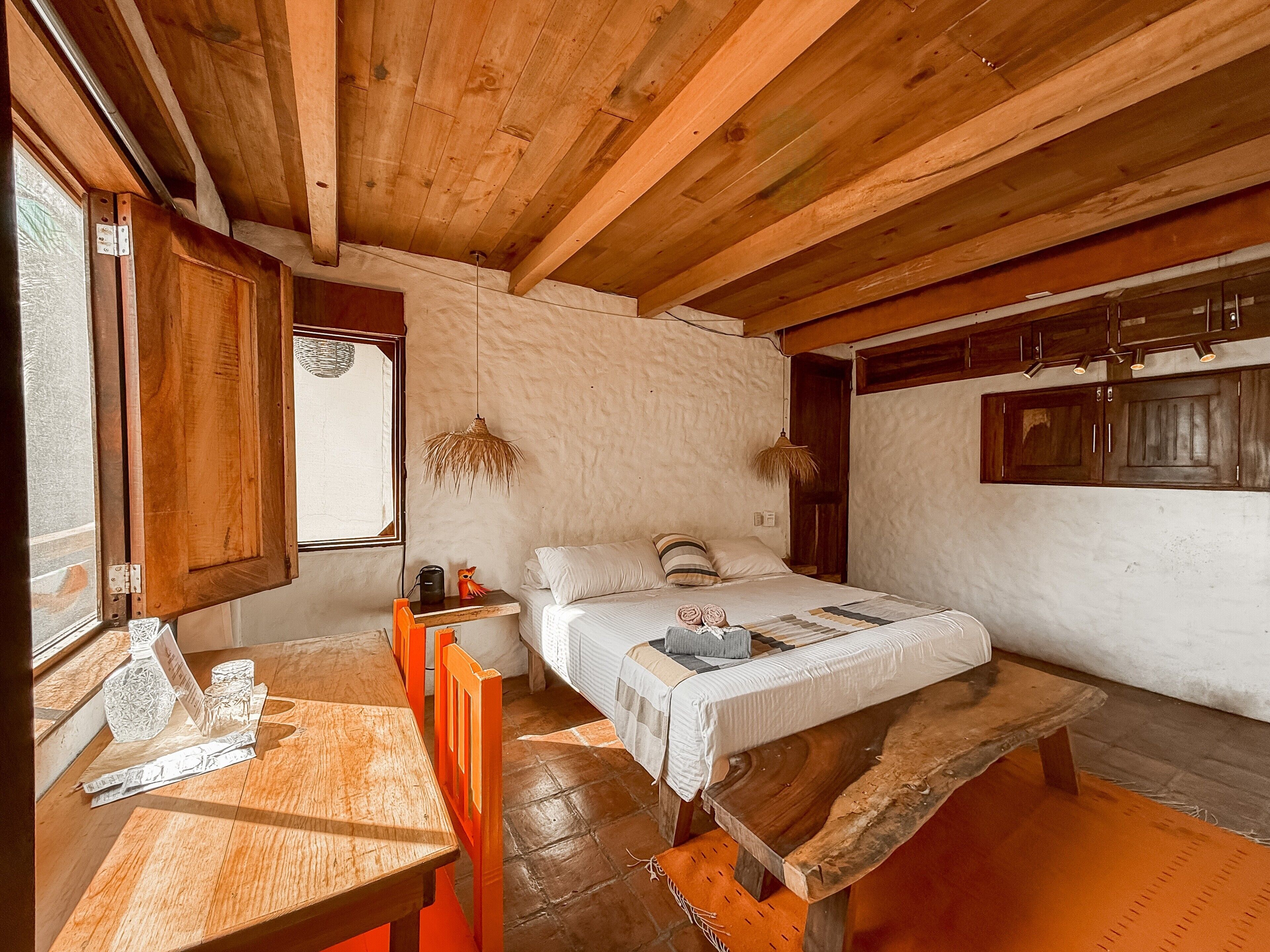 Una habitación rústica de madera con una cama, una mesa y un banco.