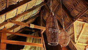 Un interior rústico con una escalera de madera, una escala y un techo tejido.