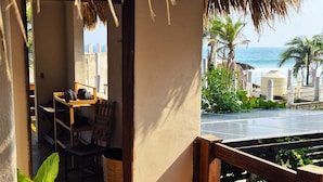 A thatched-roof balcony with a view of the sea, a wooden table, chairs, and a wicker basket. - Casa Playa del Amor (San Pedro Pochutla)