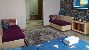 A modern bedroom with a large bed, a sofa, a TV, and a chandelier.