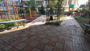 A paved walkway with playground equipment and benches.